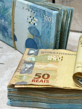 Close-up of 50 and 100 Brazilian Reais banknotes in stacks with detailed design.