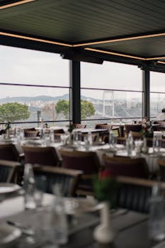 Elegant restaurant interior with a view of a city skyline through large windows.
