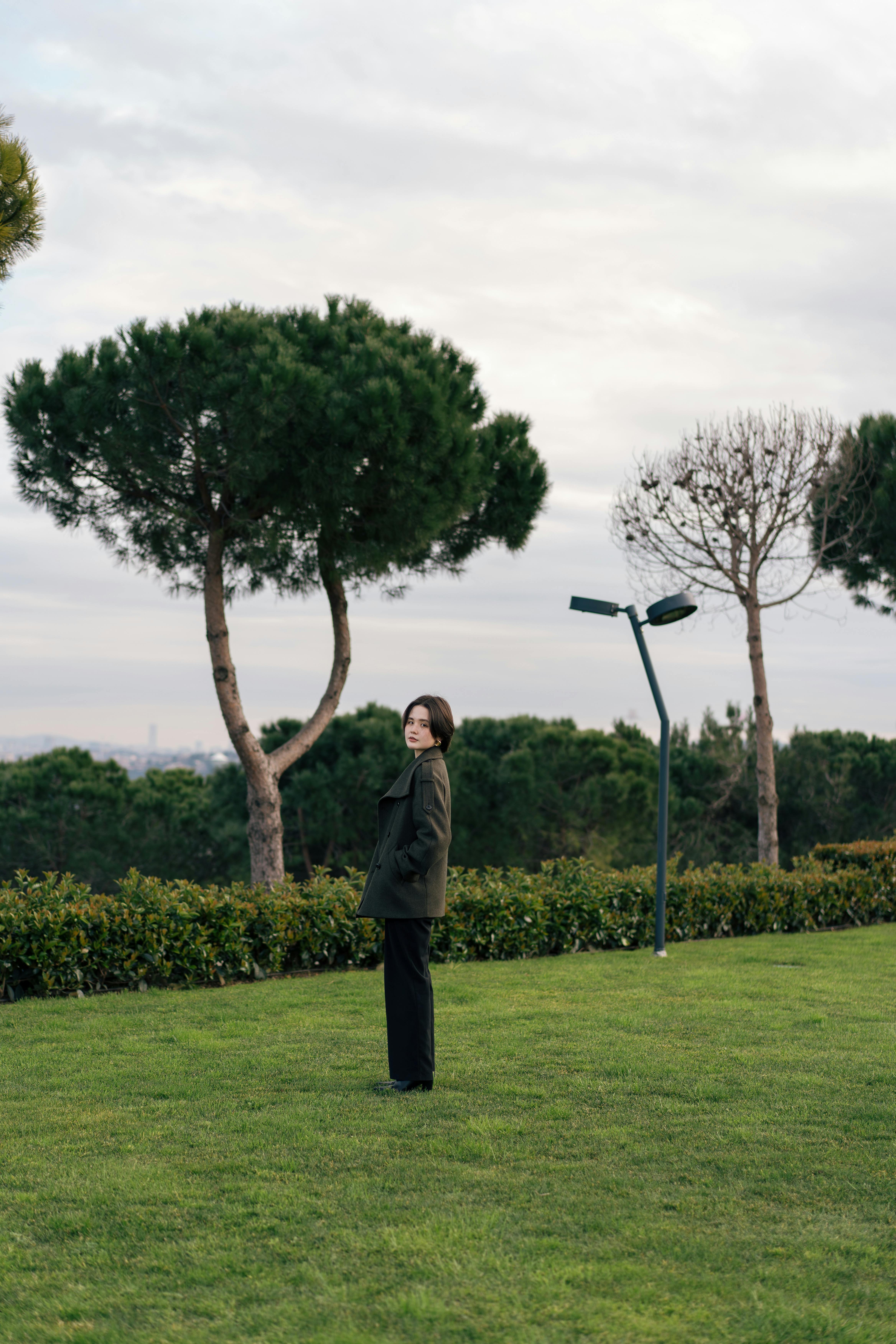A person stands in a park surrounded by pine trees in Istanbul, Turkey, showcasing natural tranquility.