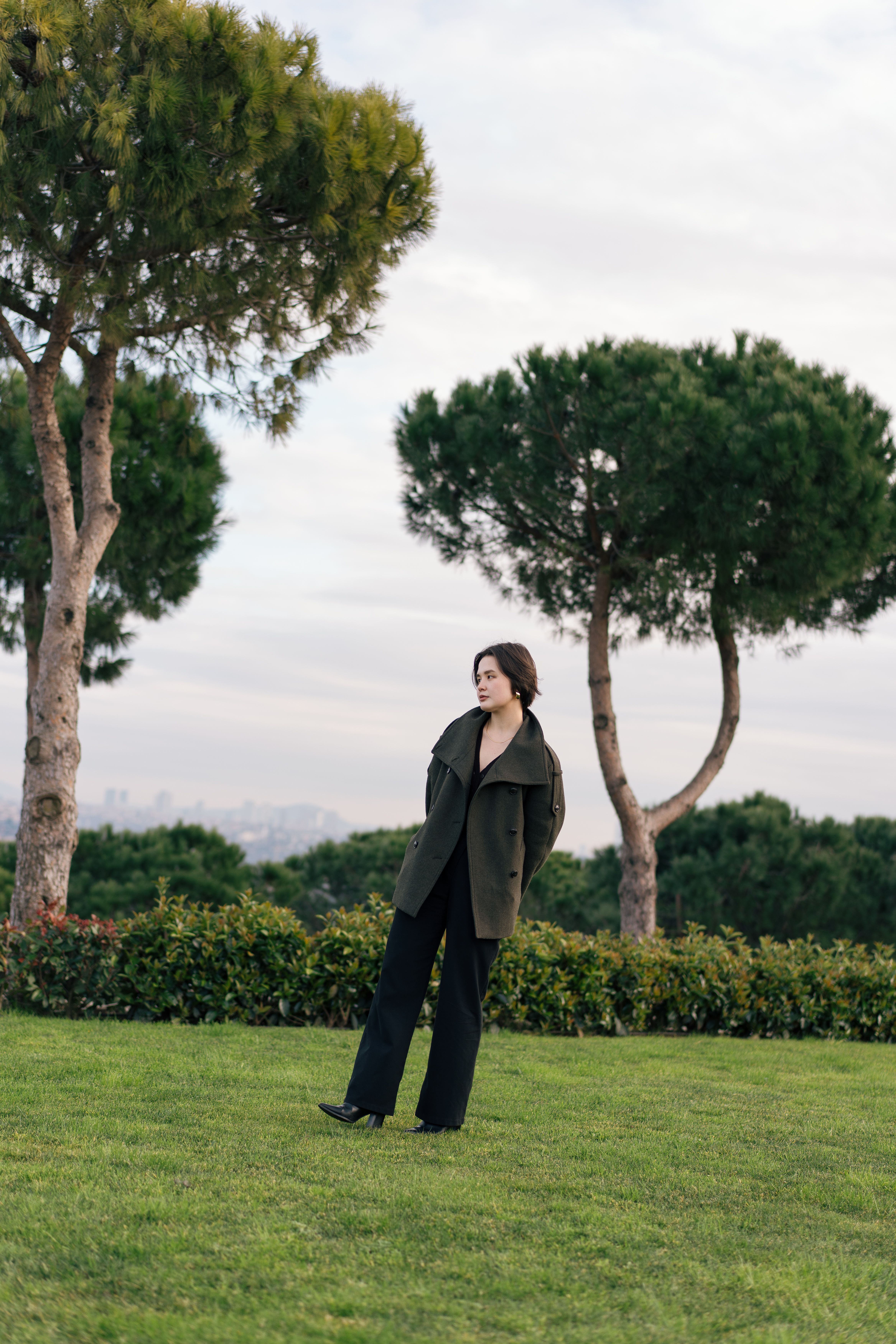 Young woman in a park surrounded by lush greenery and trees in Istanbul.
