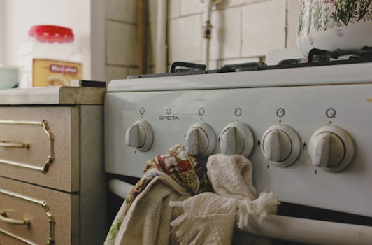 A vintage gas stove adorned with tea towels beside a kitchen counter, evokes nostalgia.