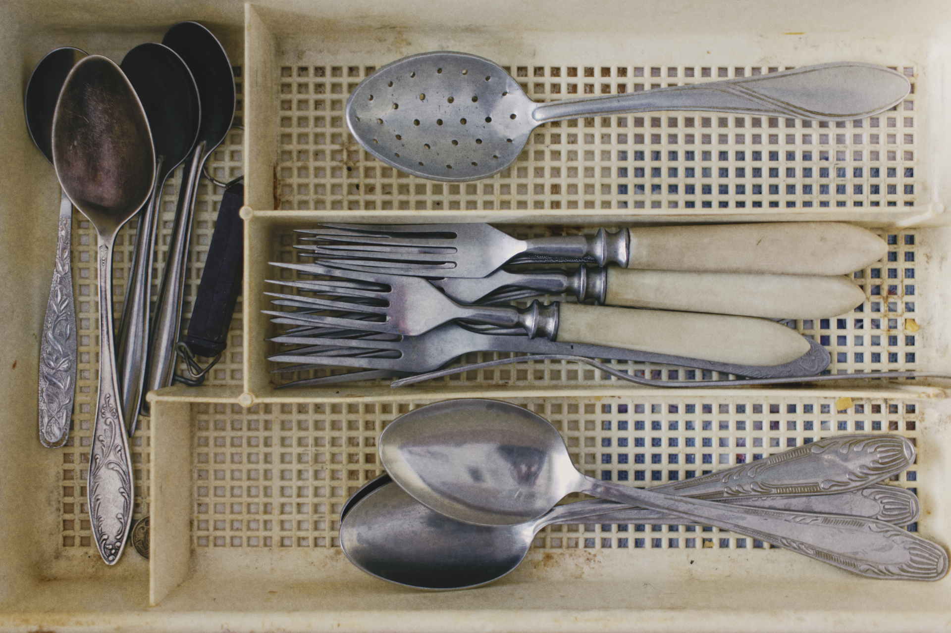 A collection of vintage silverware in an old cutlery tray, showcasing forks, knives, and spoons.