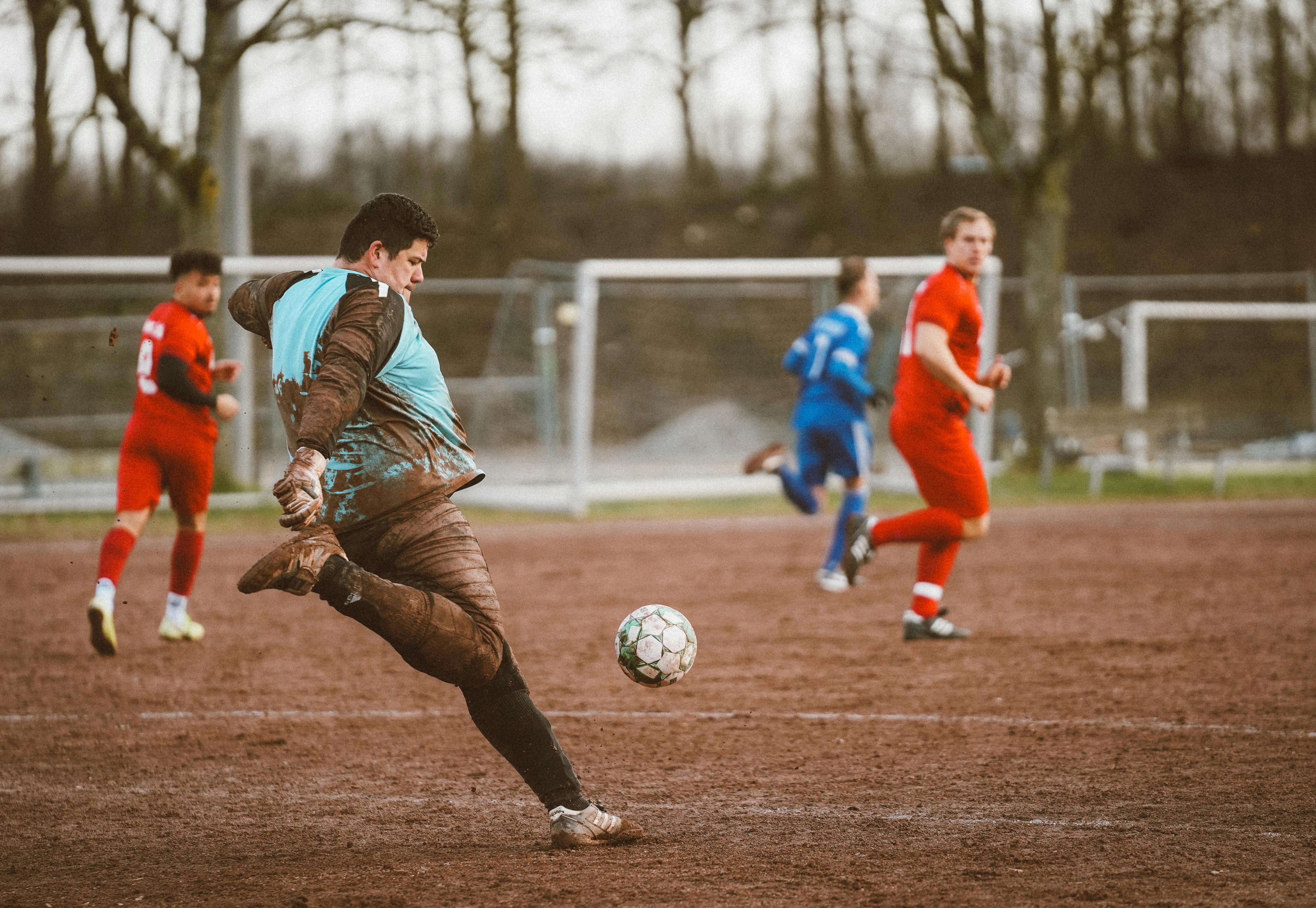 Intense action in a local soccer game on a muddy field, showcasing passionate amateur players.