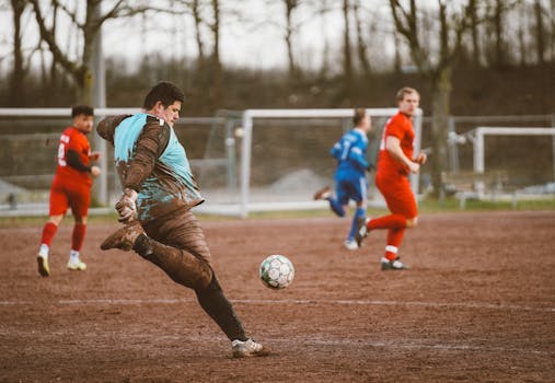 Intense action in a local soccer game on a muddy field, showcasing passionate amateur players.