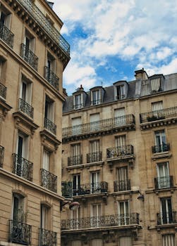 Capture of classic Parisian buildings with ornate balconies under a vibrant blue sky.