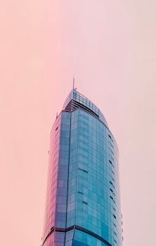 一座引人注目的玻璃摩天大楼伸入柔和的粉红色天空，展现了现代城市建筑的风貌