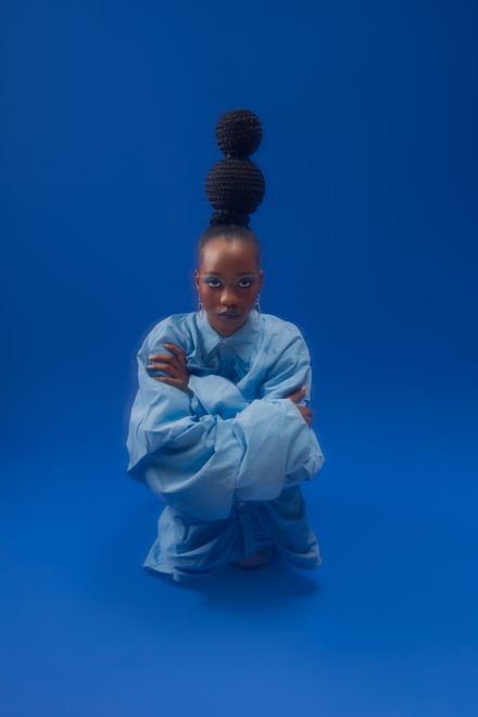 Model in layered blue tailoring on a blue studio backdrop — Omotayo Samuel on Pexels