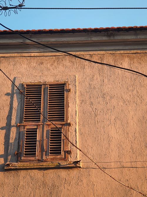 Free Old wooden shutters on a sunlit wall with crossing wires, capturing rustic charm. Stock Photo