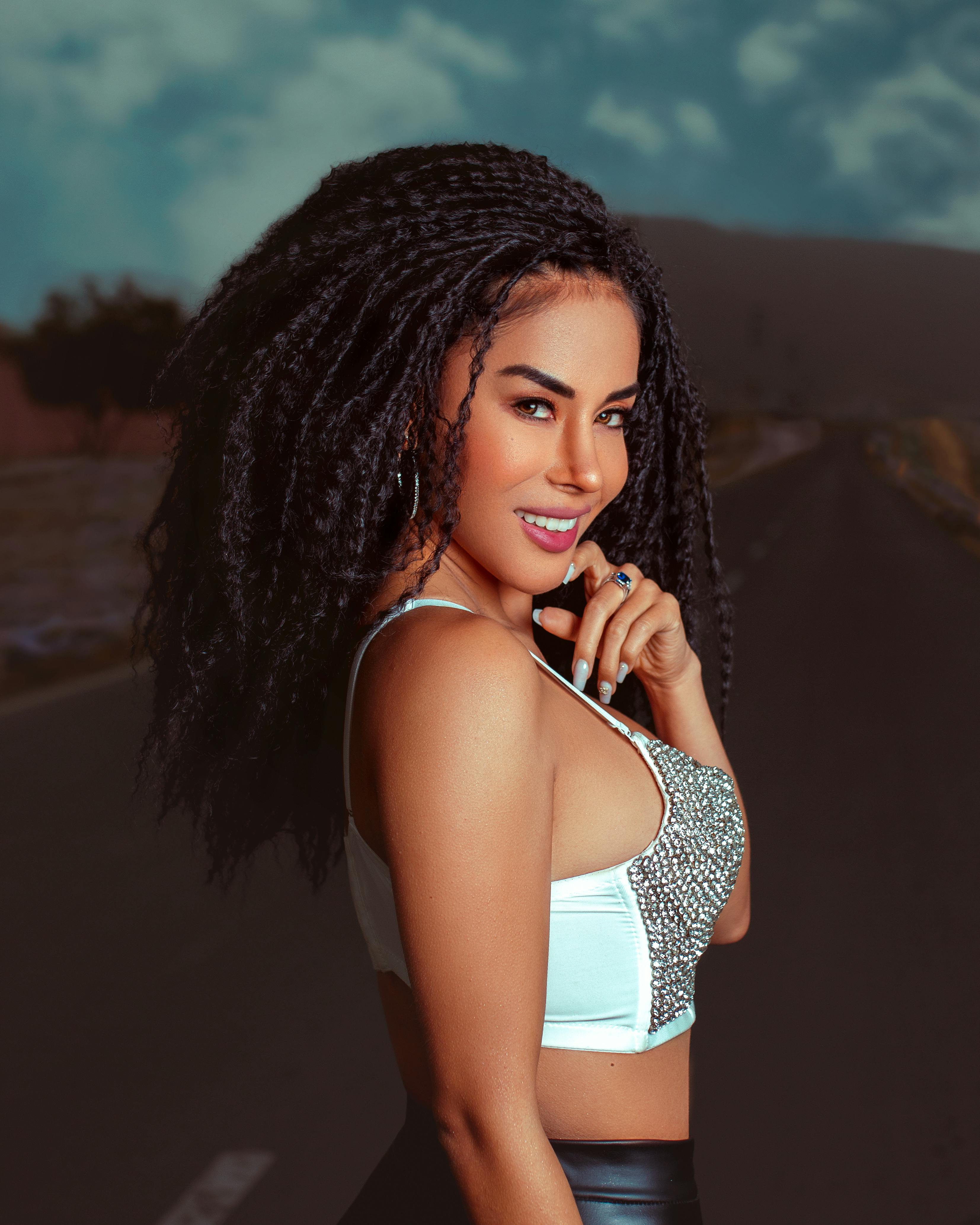 Elegant woman posing confidently on an open road, showcasing modern fashion.