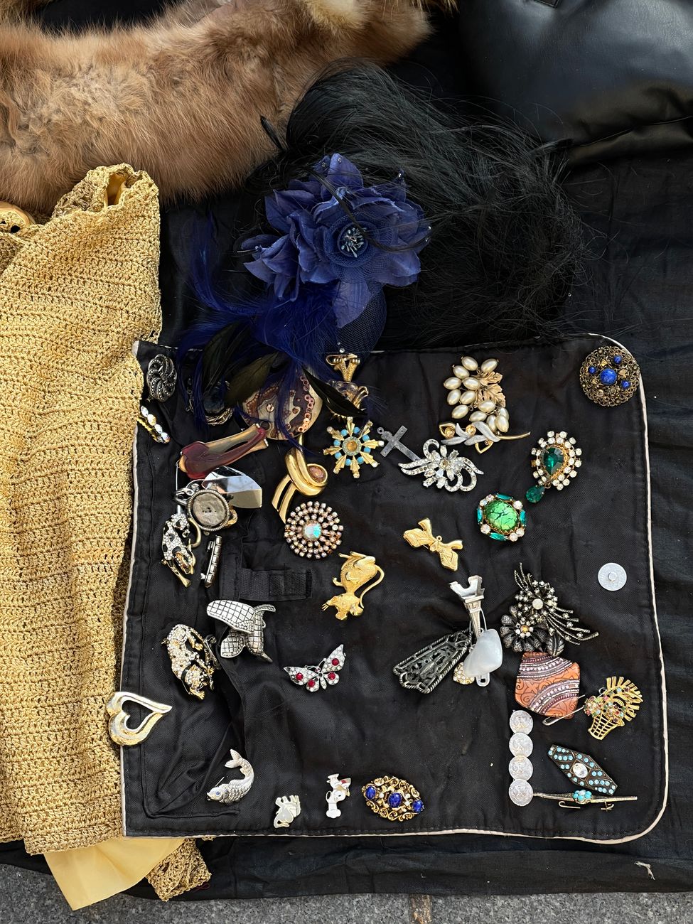 A detailed flat lay of assorted vintage brooches and costume jewelry on fabric.