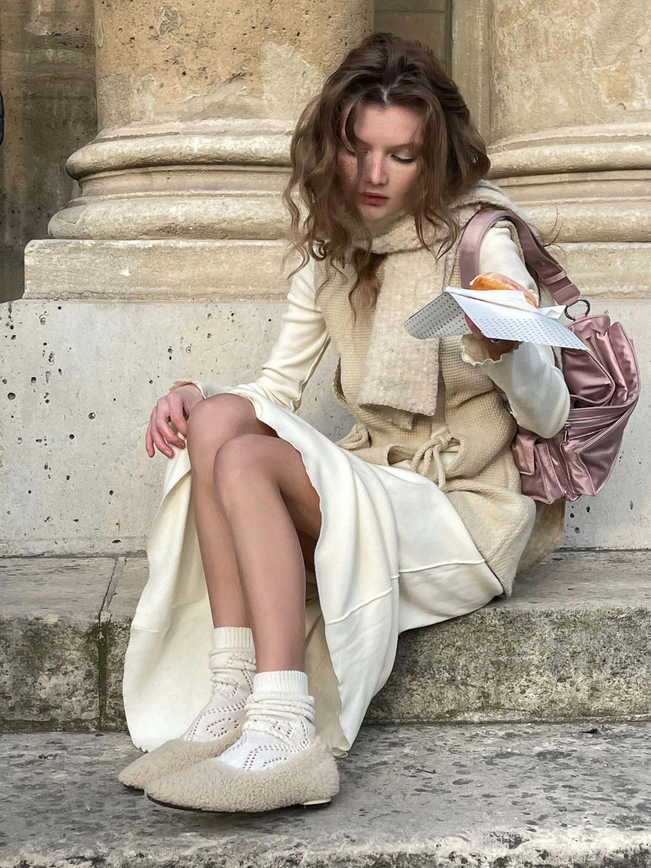 Caucasian woman sitting outdoors reading, exuding a relaxed urban vibe.