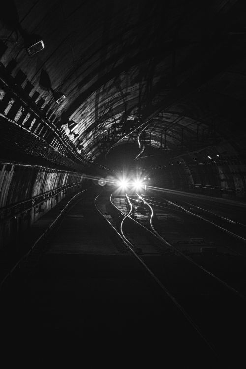 Free Monochrome view of an approaching train in a dark, moody tunnel setting. Stock Photo