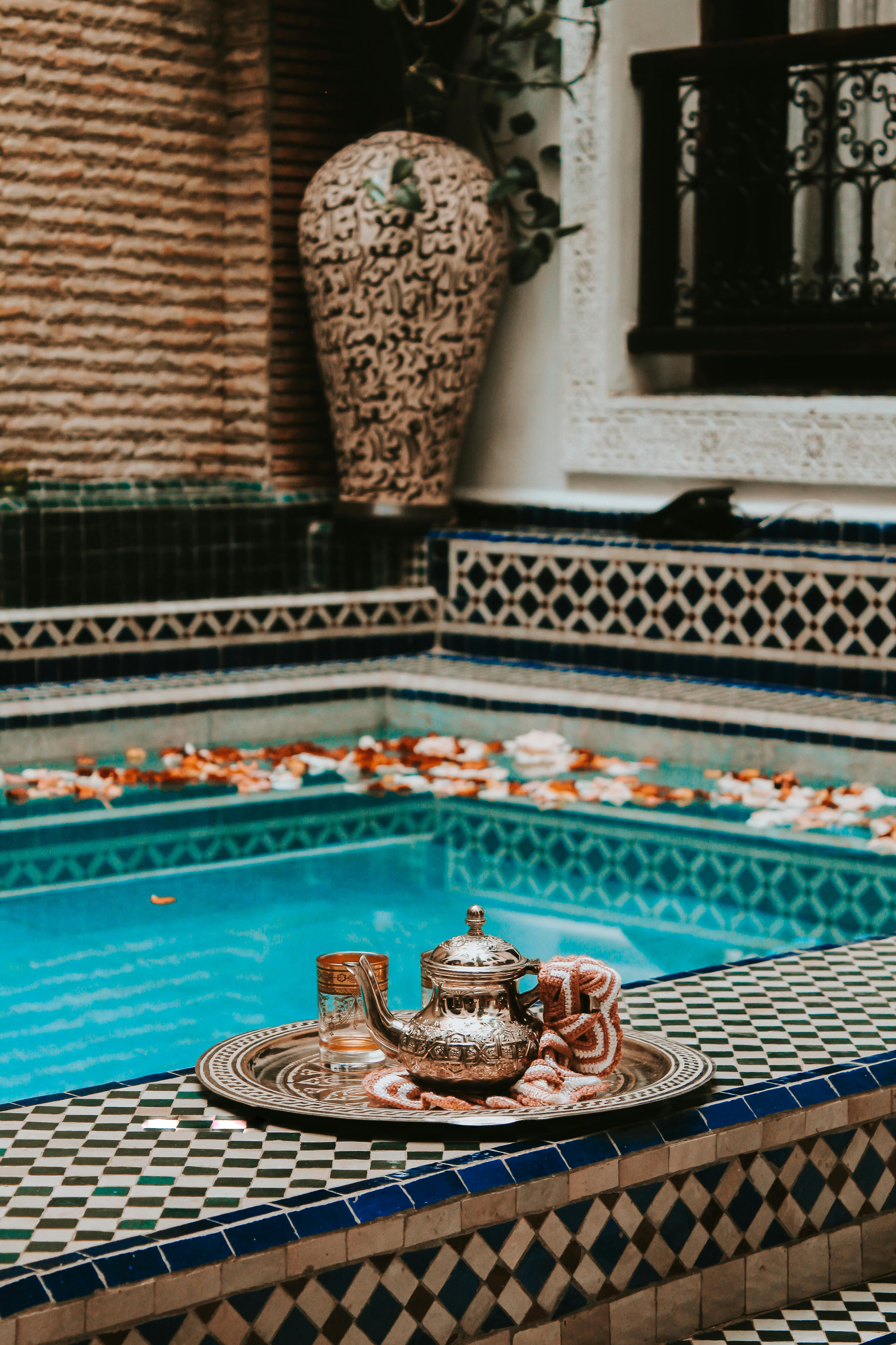 Elegant Moroccan tea setting by a vibrant pool with intricate tile designs in Marrakesh.