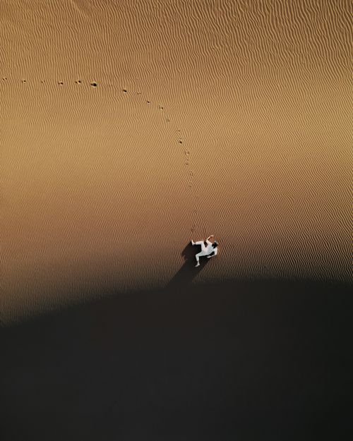 Free A lone figure walks on the sweeping sands of Merzouga, Morocco, captured from above. Stock Photo