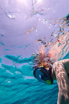 A person snorkels in vibrant blue waters, surrounded by mesmerizing sunlight reflections.