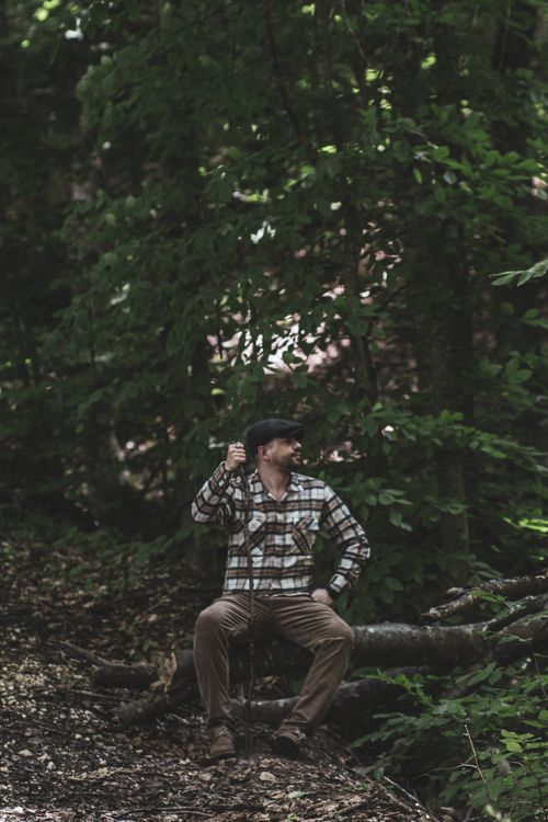 Free A hiker rests on a log in a dense forest, surrounded by lush greenery. Stock Photo