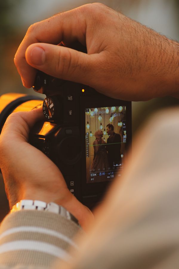 Fotógrafo sosteniendo una cámara profesional durante una sesión de boda con luz cálida