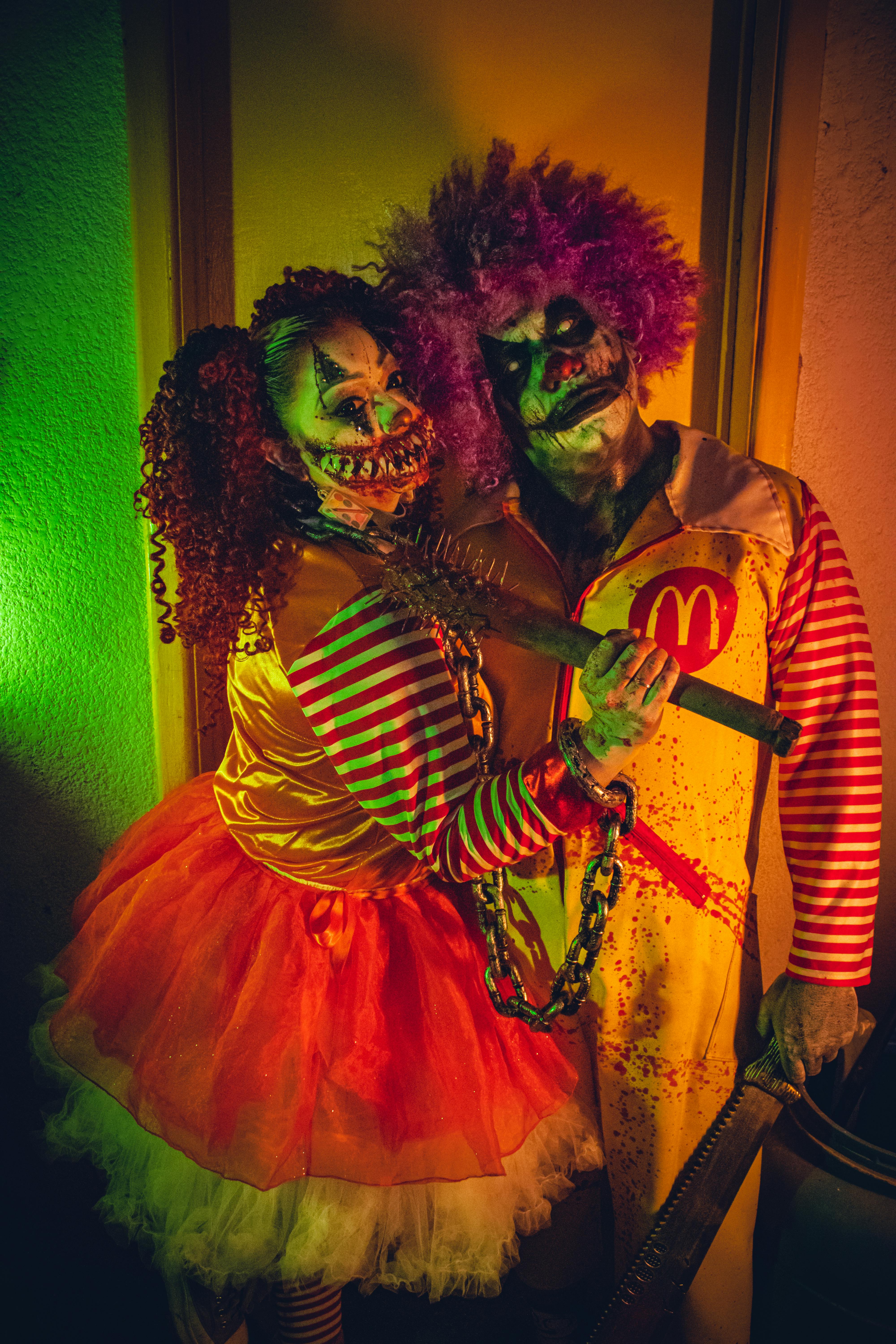 Scary clown cosplay with dramatic neon lighting in a haunting setting.