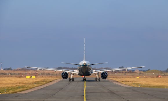 A rear view of a commercial airplane taxiing on a runway under a clear sky.