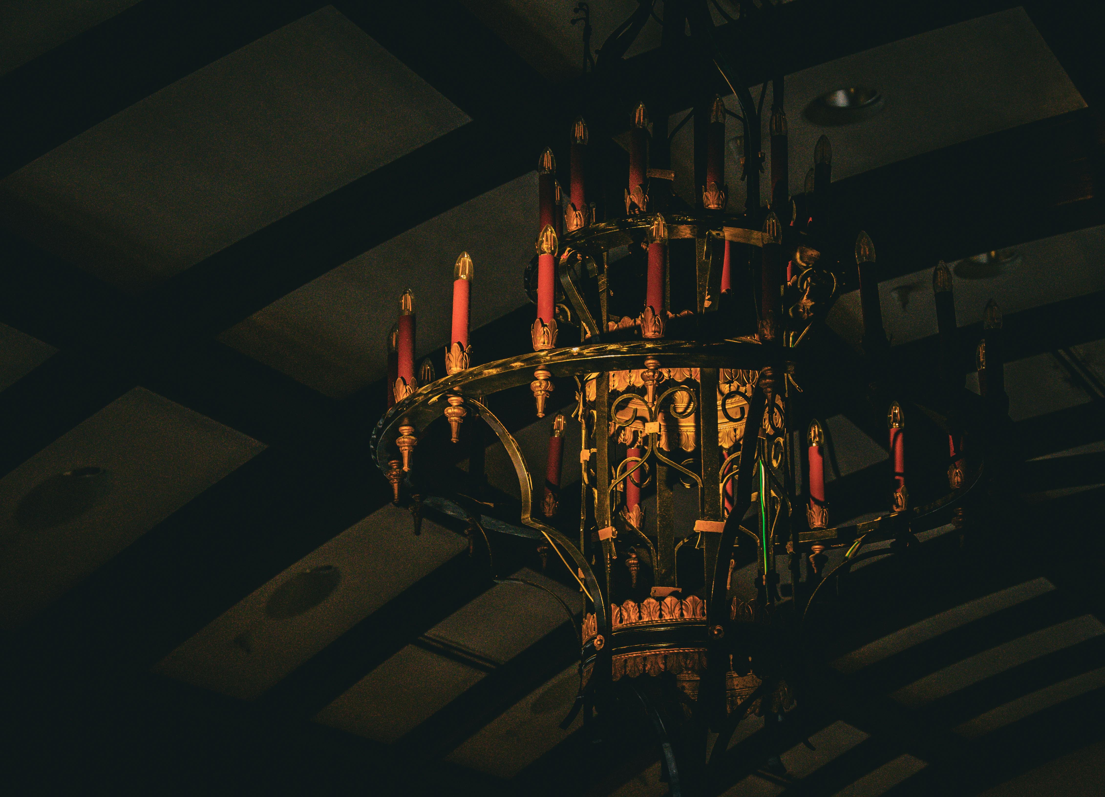 Δωρεάν Πολυέλαιος αντίκα με κόκκινα κεριά σε ένα χαμηλό φωτισμένο, ρουστίκ σκηνικό δωματίου. Φωτογραφία από στοκ φωτογραφιών