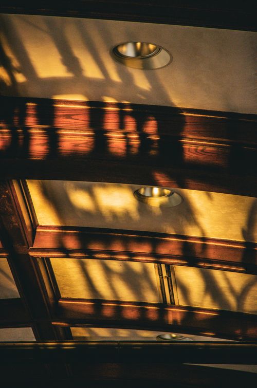 Free Warm sunlight casting shadows on a wooden ceiling interior architecture detail. Stock Photo