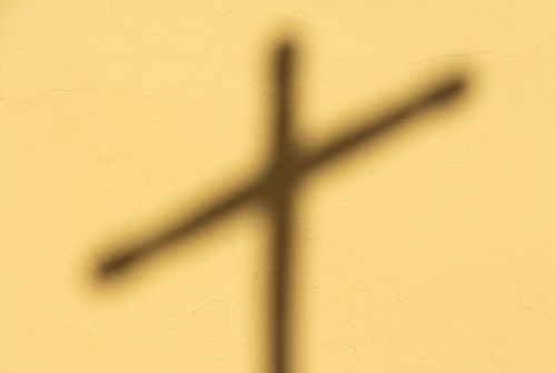 Free Soft shadow of a cross cast on a textured yellow wall. Stock Photo