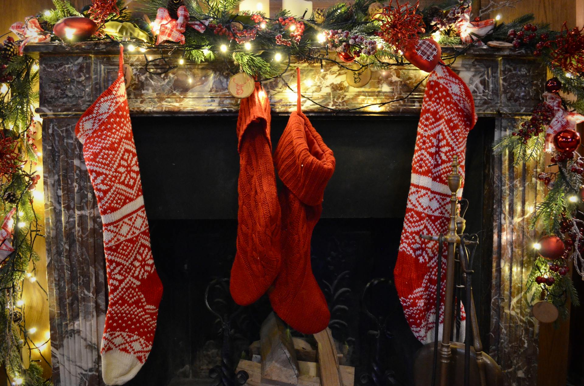 Festively decorated fireplace with Christmas stockings and twinkling lights, capturing holiday spirit.