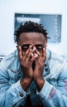 一位时尚的黑人，留着辫子，穿着牛仔夹克，若有所思地摆出姿势