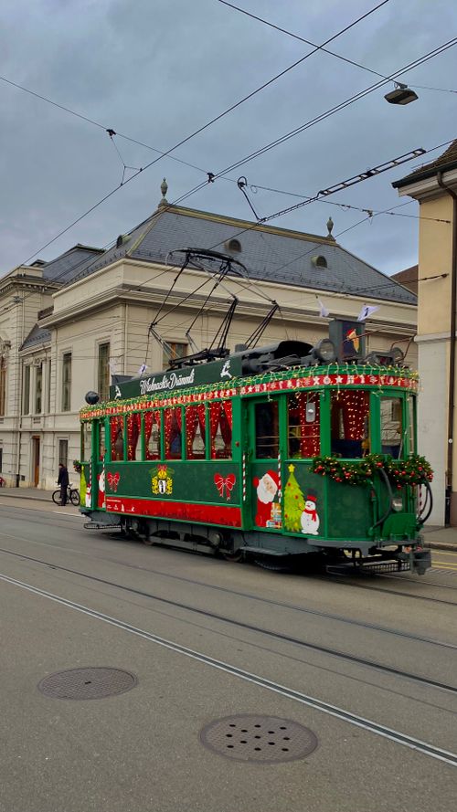 Free A green tram decorated for Christmas on a city street, exuding holiday cheer. Stock Photo