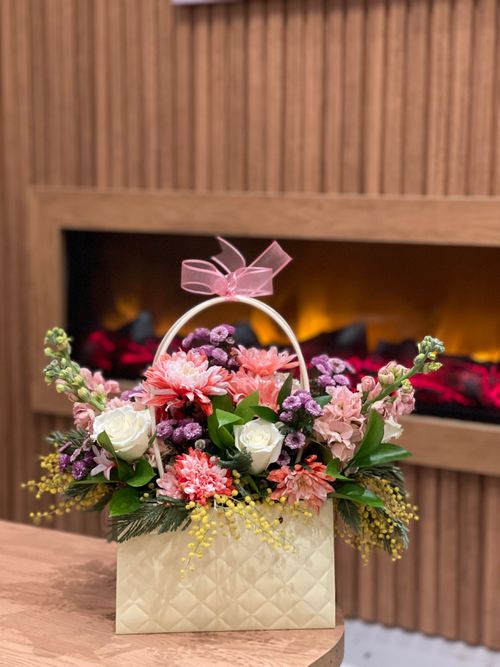 Free Chic floral bouquet with a pink ribbon in a quilted vase by a modern fireplace. Stock Photo
