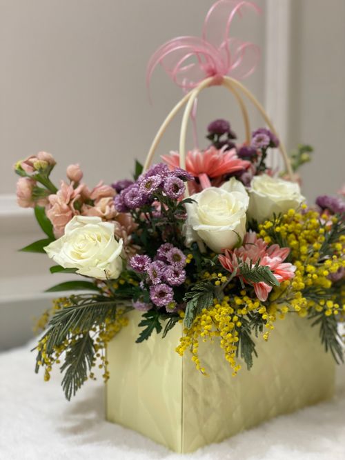 Free Charming floral arrangement featuring roses, chrysanthemums, and mimosa in a decorative box. Stock Photo