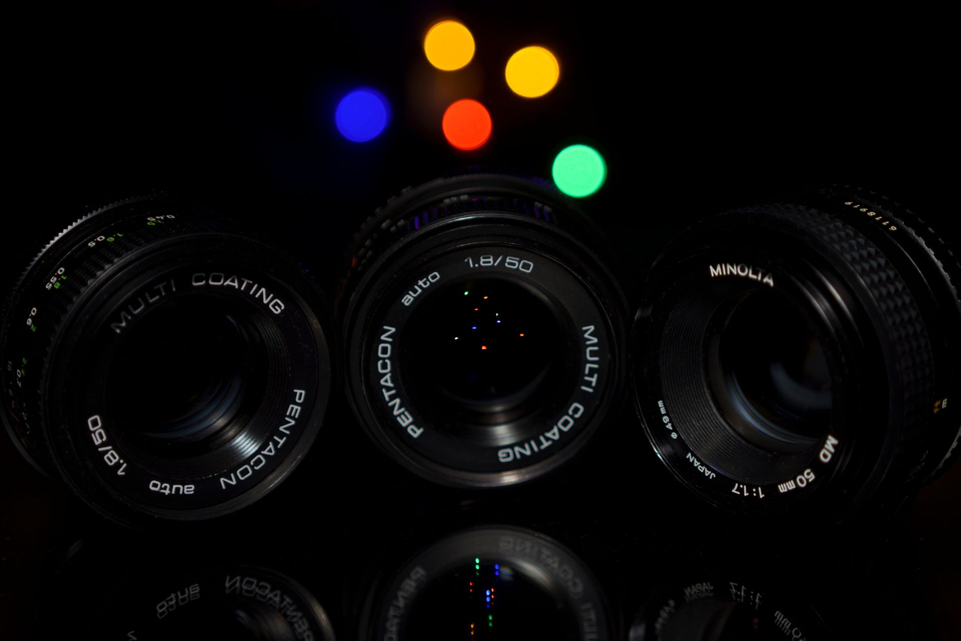 Three vintage camera lenses with vibrant bokeh light effects in the background, UK setting.