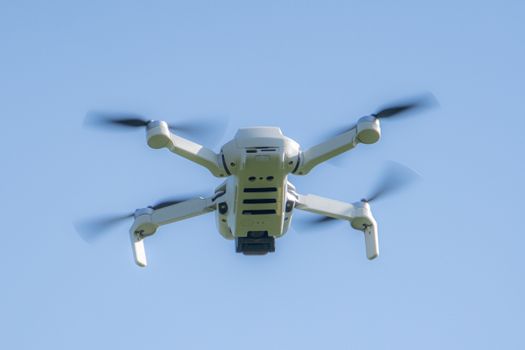 Aerial view of a modern drone soaring through a clear blue sky in the UK.