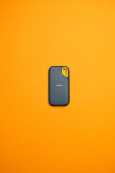 Compact portable SSD against a bold orange backdrop, showcasing modern sleek design.