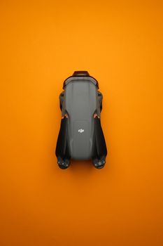Top view of a compact gray drone, sharply contrasting with a vivid orange backdrop.