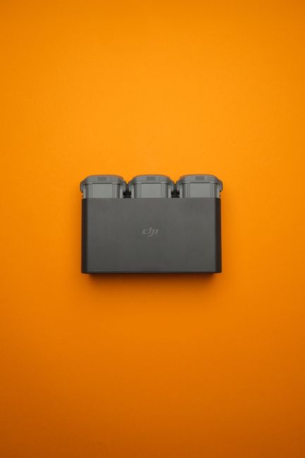 Compact DJI battery charger against a bright orange backdrop. Perfect for drones.