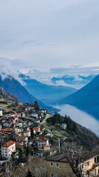 Charming village nestled in mountains with stunning lake view under a clear sky.