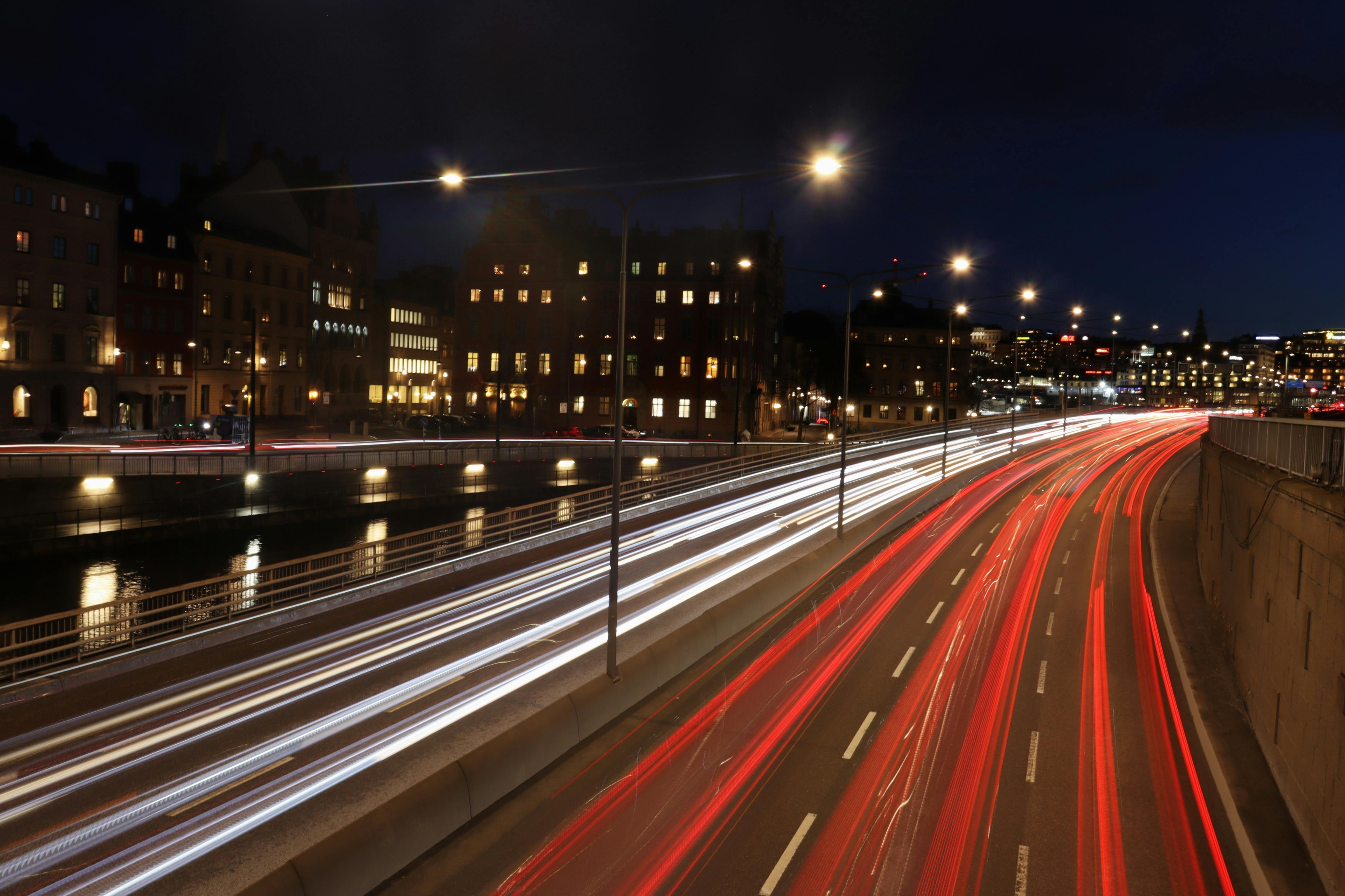 Long exposure of city traffic at night with blurred light trails and streetlights.