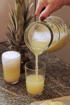 Fresh pineapple juice being poured into a glass, epitomizing tropical refreshment.