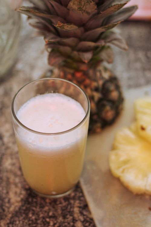 Free Glass of fresh pineapple juice beside whole pineapple and slices. Stock Photo