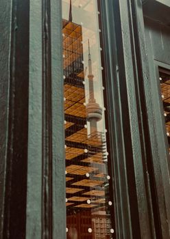 Stylish reflection of Toronto's CN Tower in a contemporary building window with urban design elements.
