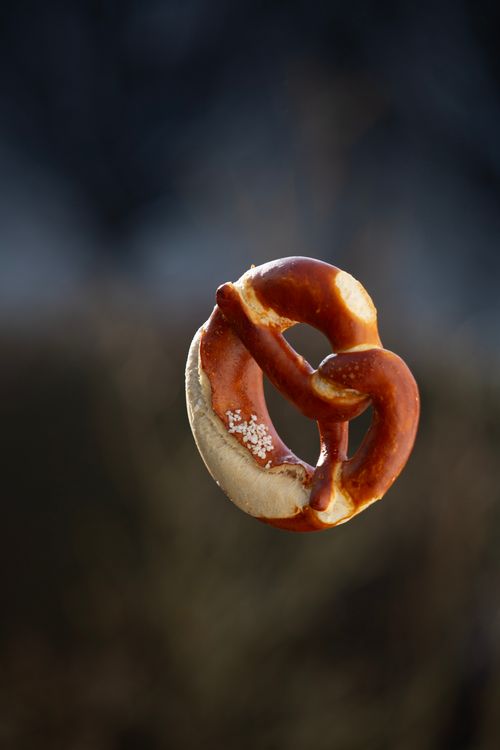 Free A single salted pretzel appears to be floating with a contrasting blurred background. Stock Photo