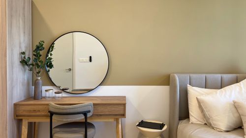 Free A cozy bedroom featuring a wooden vanity, mirror, and soft textiles, perfect for modern interior design. Stock Photo