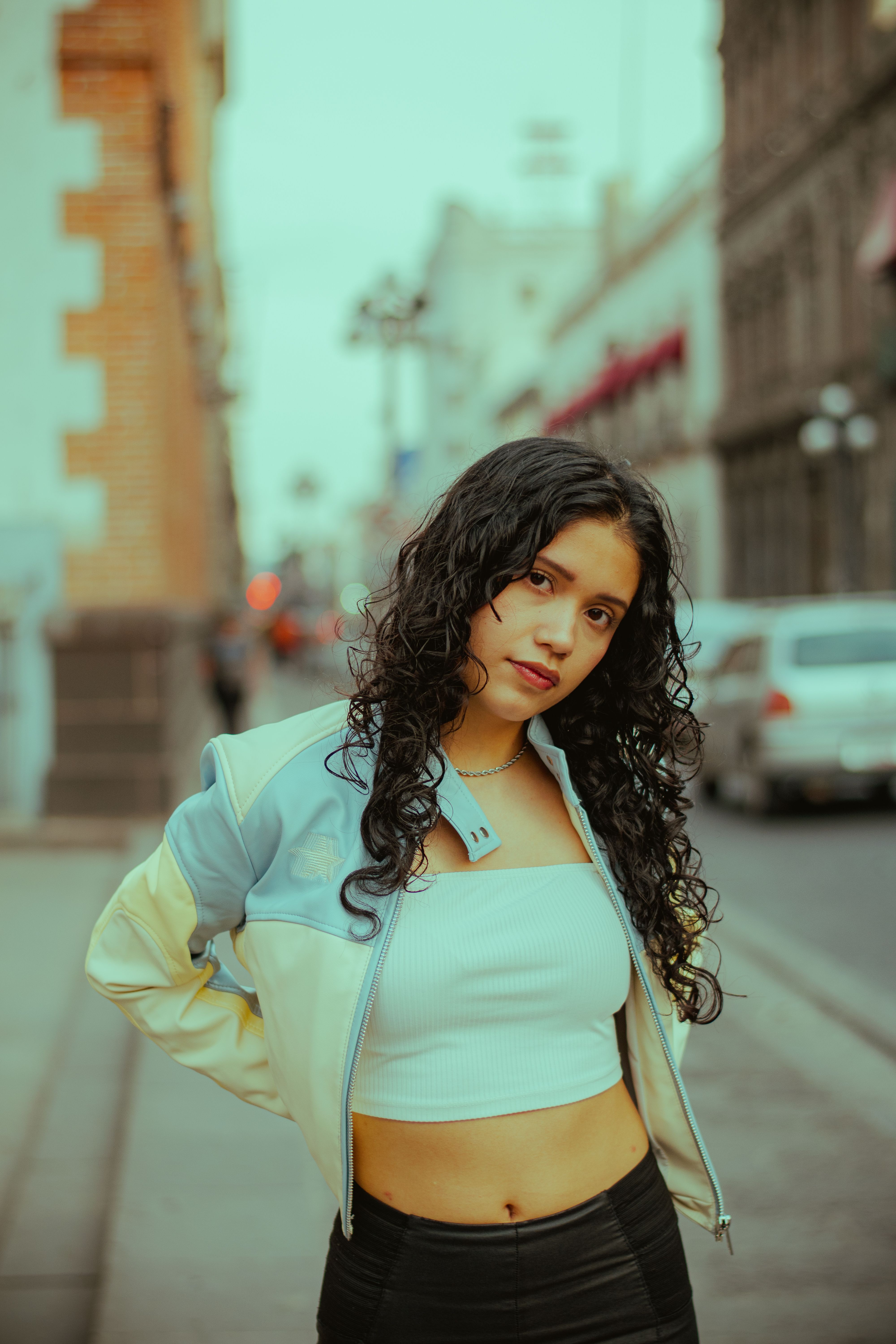 Fashionable young woman poses confidently on a vibrant city street.
