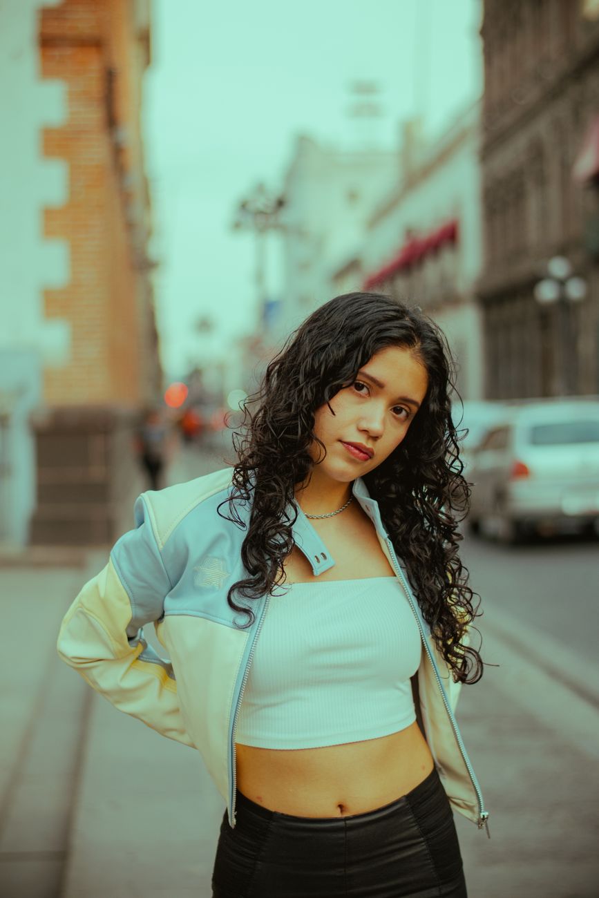 Fashionable young woman poses confidently on a vibrant city street.