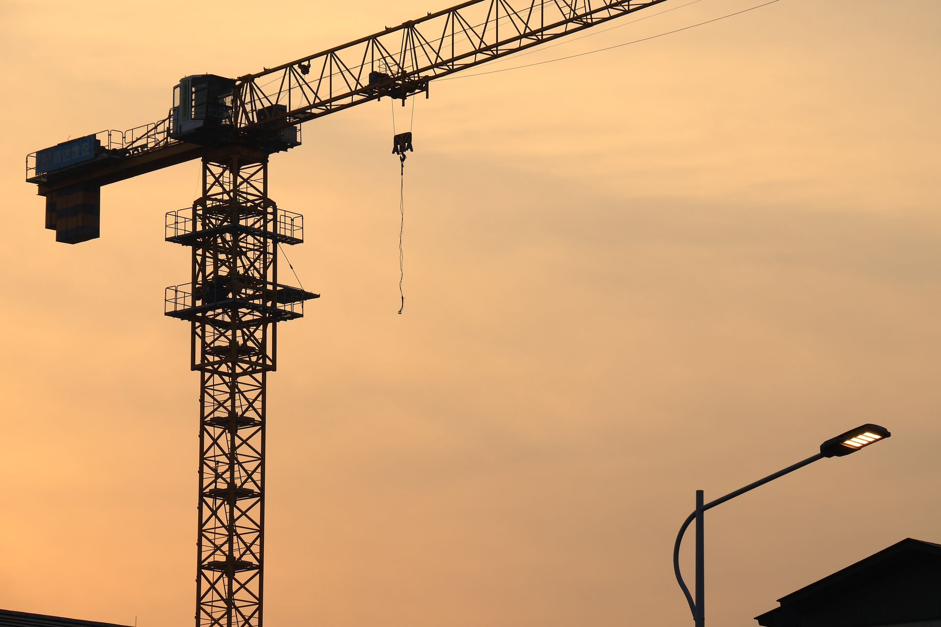 Silhouette of a construction crane at sunset, urban development background.