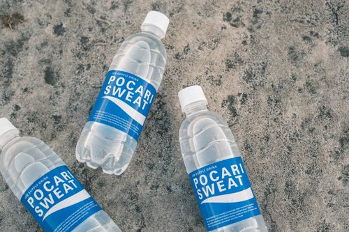 Free Three Pocari Sweat bottles arranged on a textured concrete surface. Stock Photo