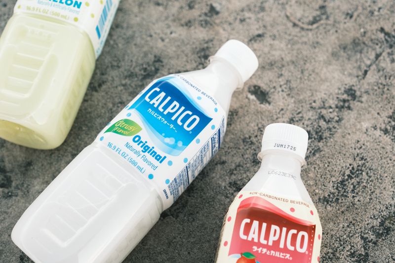 Close-up of Calpico beverage bottles on textured concrete surface.