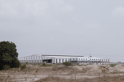 Free A large industrial building set in an empty rural landscape under a cloudy sky. Stock Photo