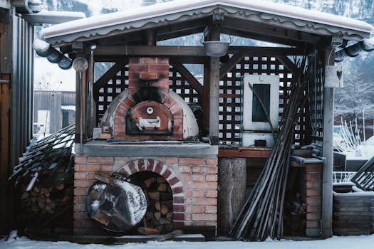 Brick pizza oven surrounded by snow, evoking a rustic alpine retreat feel.